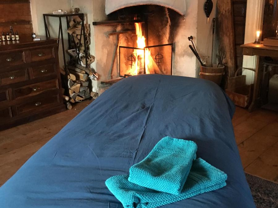 En säng framför brinnande eld i öppna spisen. 