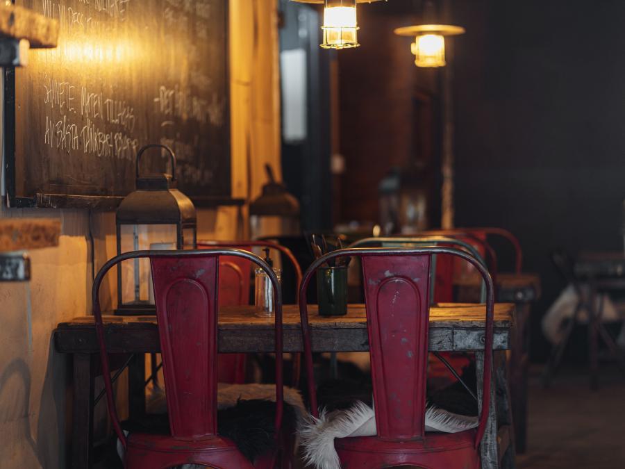 Restaurangen interiör, stolar med röda ryggar, rustika bord, svart tavla med menyn skriven med vit krita. 