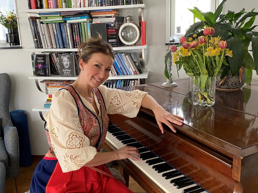 Sonja Aldén sitter vid pianot i Malungsdräkt.