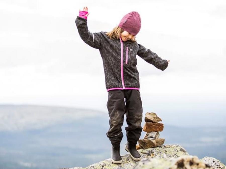 En glad flicka står på en sten.