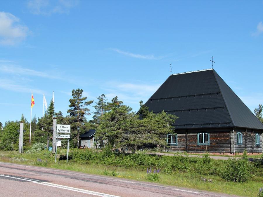 The church with greenery around and the country road next to it.