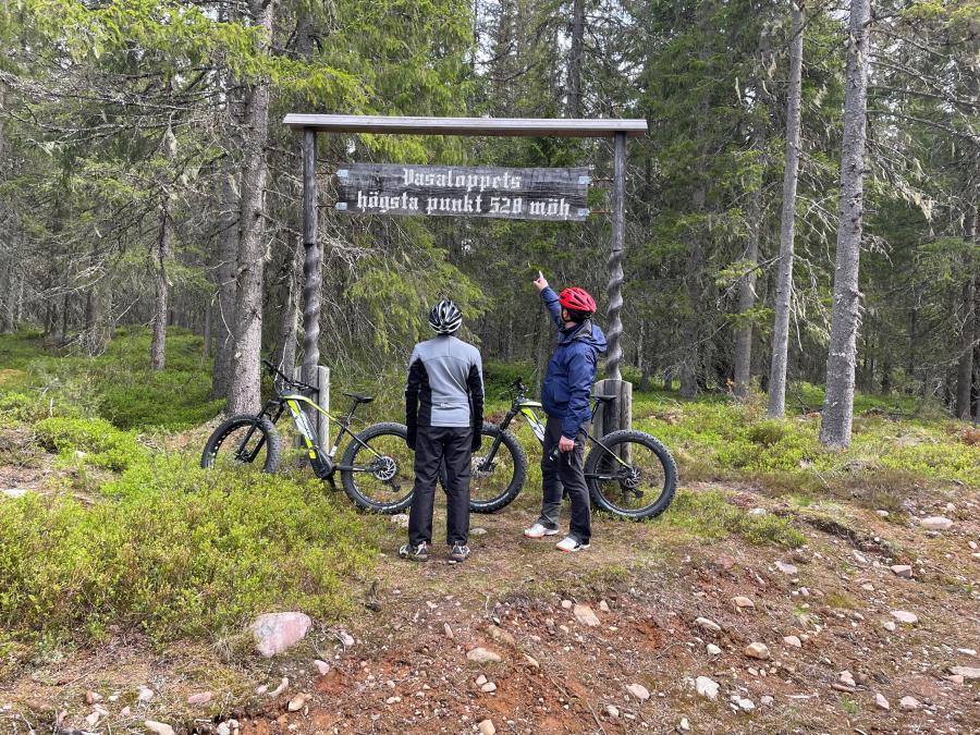 Two persons by their Electric-MTB at a sign in the forest.