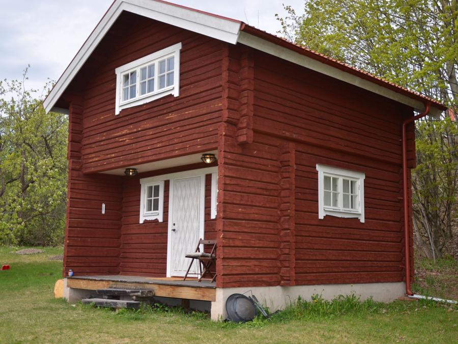 Red log cabin with white windows and door.