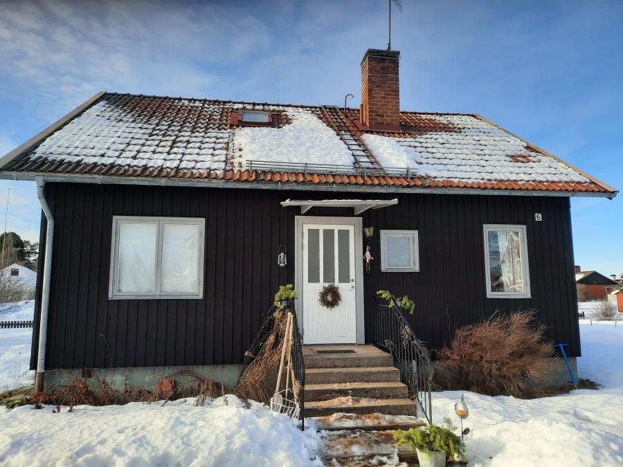 Dark brown house with snow on the roof.