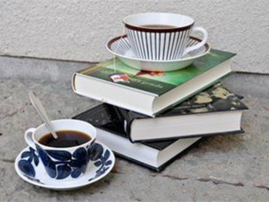 Böcker travade på varandra och en kaffekopp.