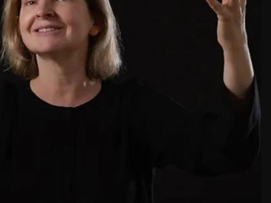 En kvinna i svart tröja som sträcker upp ena handen.