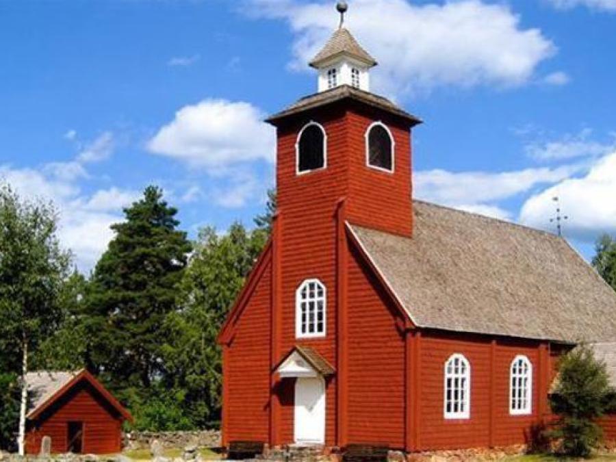 Envikens Gamla kyrka, rör träkyrka med vit port och vitt kyrktorn.