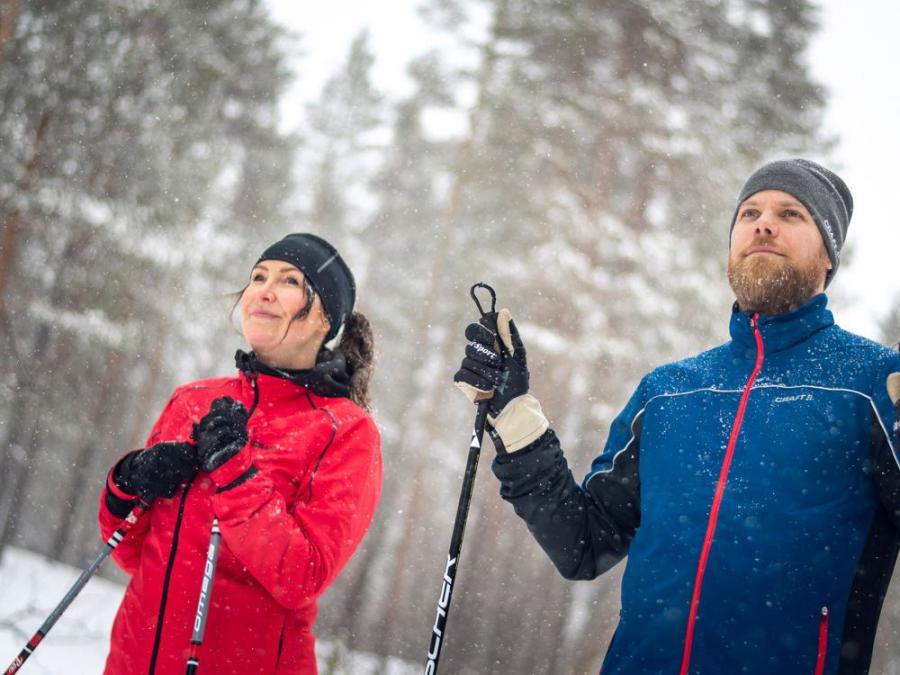 A man and a woman in ski clothes with poles in their hands.