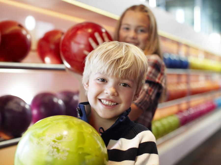Boy and girl with bowling balls in their arms.