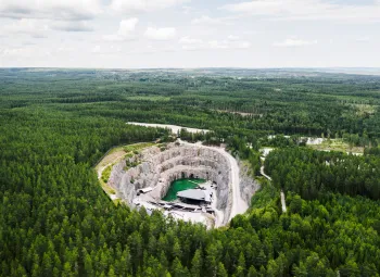 Flygbild över Dalhalla där man tydligt ser kalkbrottet och grön skog runtomkring.