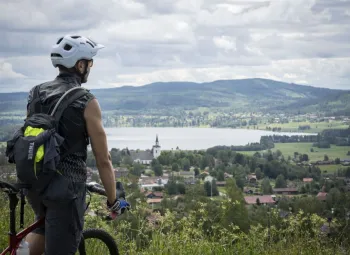 Kille med cykel står och blickar ut över fina utsikten över byn Siljansnäs och Granberget i bakgrunden.