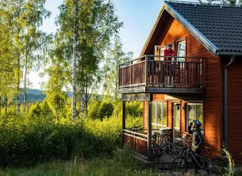 A red cottage on two floors, cyclist in front of the cottage.