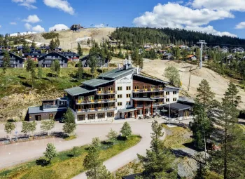 A building with trees and mountains in the background.