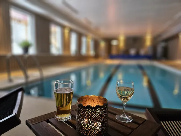 Bassäng med en ljuslykta och två glas i förgrunden.