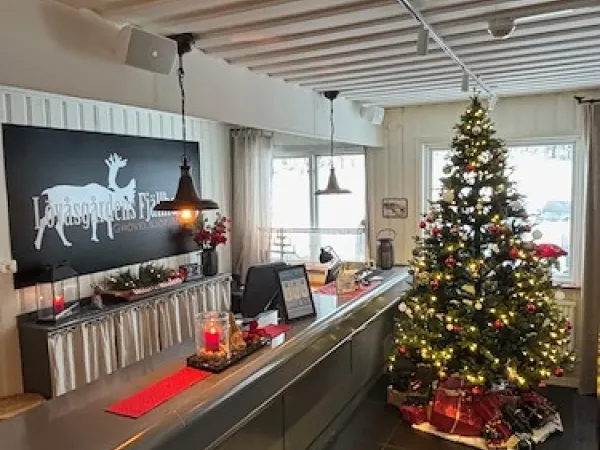 Juldekorerad receptionsdisk med en fint klädd julgran bredvid.