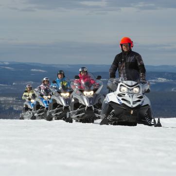 Six snowmobiles on a track.