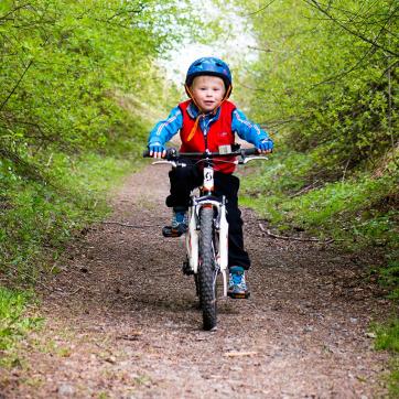 Barn på cykel på skogsväg.