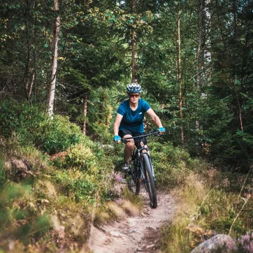 Tjej som cyklar längs en skogsled.