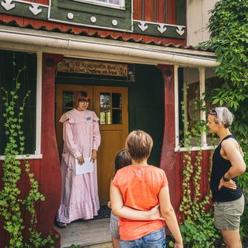 Två kvinnor och en guide står utanför Carl Larsson-gården.