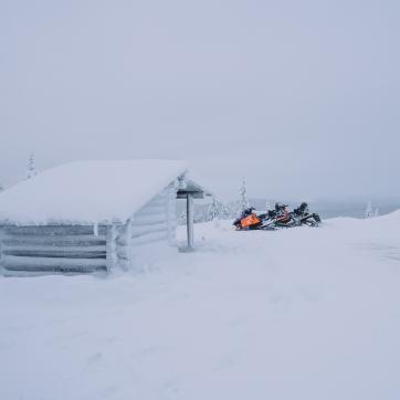Snowmobile parked at a hut.