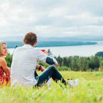 A couple in a meadow looks out over Siljan.
