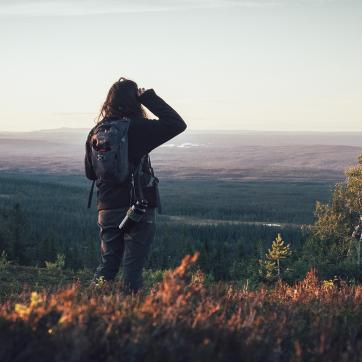 A woman with a backpack looks out over the mountain.