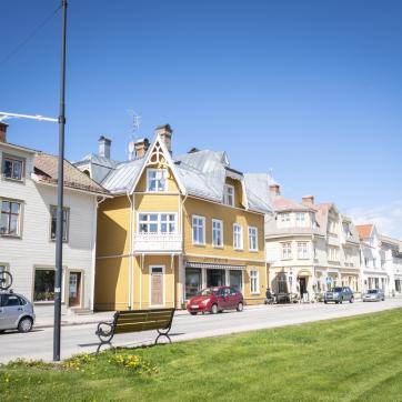 Vansbro, vita och gula hus längs en gata bredvid en grön gräsmatta.
