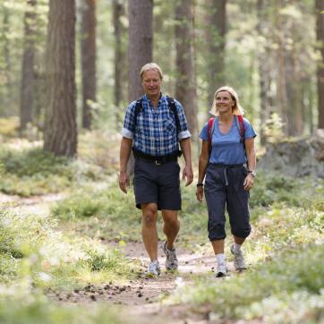 Elderly couple hiking on trail in the woods.