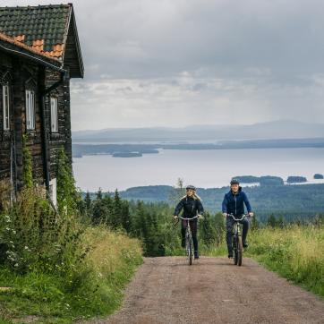 Couple cycling on a gravel road in Fryksås.