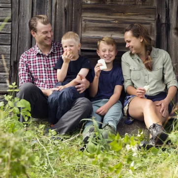 Familj som sitter mot ett härbre.