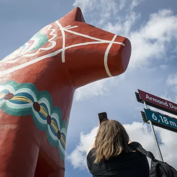 En kvinna fotar en gigantisk dalahäst.