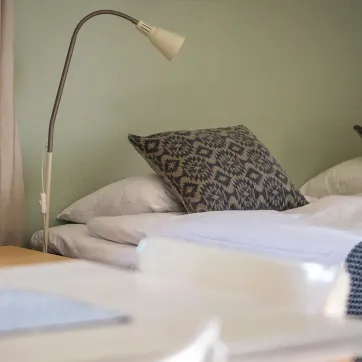 Ett hotellrum med skrivbord, bäddad säng och en sänglampa.