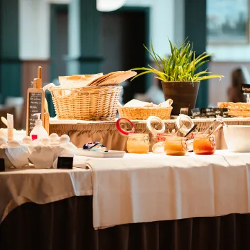 A breakfast buffet is laid out on a table with a white tablecloth.