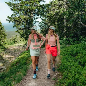 Två kvinnor går på en vandringsled i skogen.