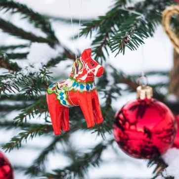 En dalahäst och julgransprydnader hänger i en gran.
