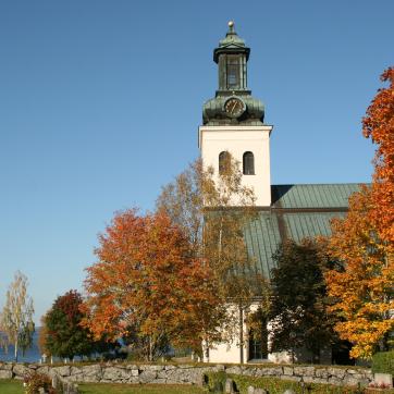 Söderbärkes kyrka med träd i höstfärger framför.
