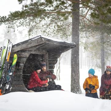 En familj grillar i snön vid ett gapskjul.