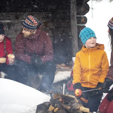 Familj som myser i snön vid en slogbod