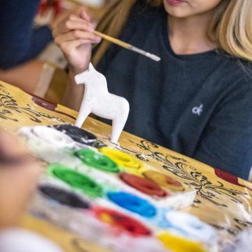 Barn som målar dalahästar.