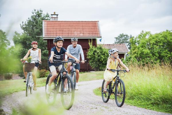 Familj som cyklar längs en grusväg.