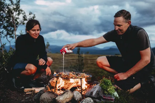 A couple cooking food outside.