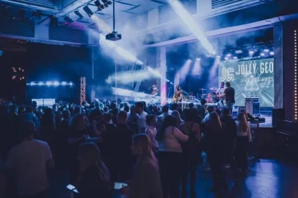 Publik som står och tittar på ett band på en scen.