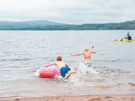 Badande barn, en kajak i bakgrunden.