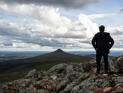 En man som står på ett berg och ser ut över området.
