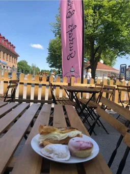 På ett bord står ett uppdukat fat med fikabröd, rosa beachflagga med text Gustafs bröd.