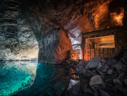 A cave with a small building and a pool of water.