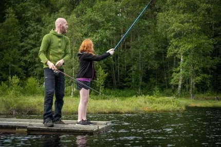Far och dotter fiskar från en brygga.