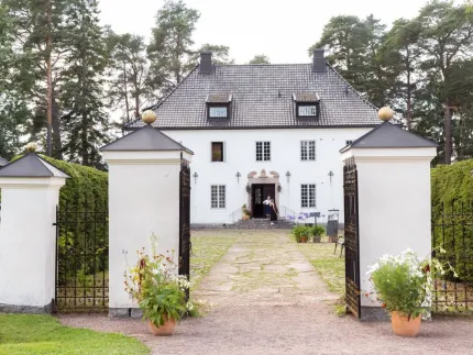 Vitt stenhus med två stora vita grindstolpar i sten med gång in till huset.