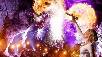 En person som håller en eld framför en grotta.