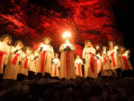 En grupp människor i vita kläder med ljus i sina händer.